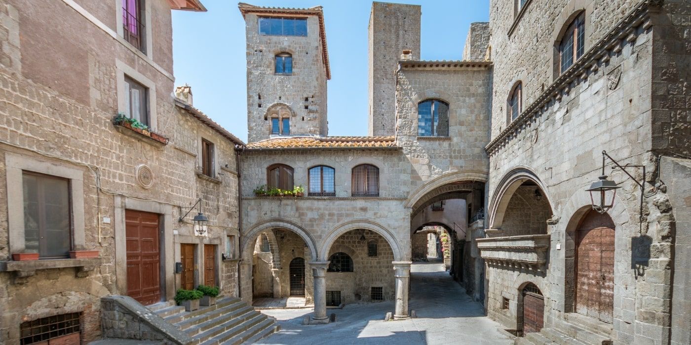 Piazza San Pellegrino nel quartiere medievale di Viterbo con archi e palazzi in peperino